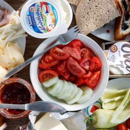 Delicious breakfast setup with cheese, cold cuts, bread, and fresh vegetables.