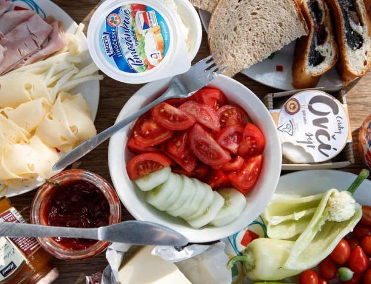 Delicious breakfast setup with cheese, cold cuts, bread, and fresh vegetables.